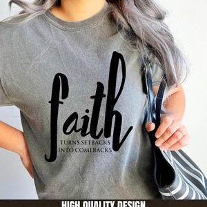 May include: A gray t-shirt with the word "faith" written in black cursive lettering. The text below the word "faith" reads "turns setbacks into comebacks".
