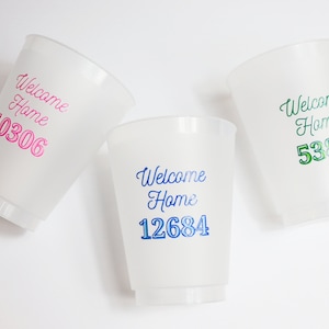 以下が含まれることがあります： 白いプラスチック製のカップが3つあり、それぞれに「Welcome Home」という言葉と番号が印刷されています。カップは白い背景の上に置かれています。番号は10306、12684、5381です。番号はピンク、青、緑の異なる色で印刷されています。