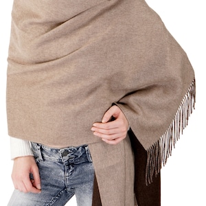 May include: A brown and dark brown reversible shawl with fringe. The shawl is draped over a person's shoulders and tied at the waist.