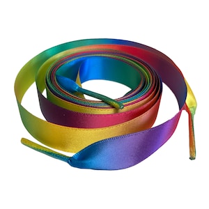 May include: Rainbow shoelaces made of satin ribbon. The shoelaces are tied in a loop and feature a gradient of colours, including red, orange, yellow, green, blue, indigo, and violet.