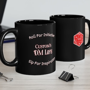 May include: Two black ceramic mugs with white text and a red 20-sided die graphic. The mug on the left says "Roll For Initiative Custom's DM Life Sip For Inspiration". The mug on the right has a red 20-sided die graphic.