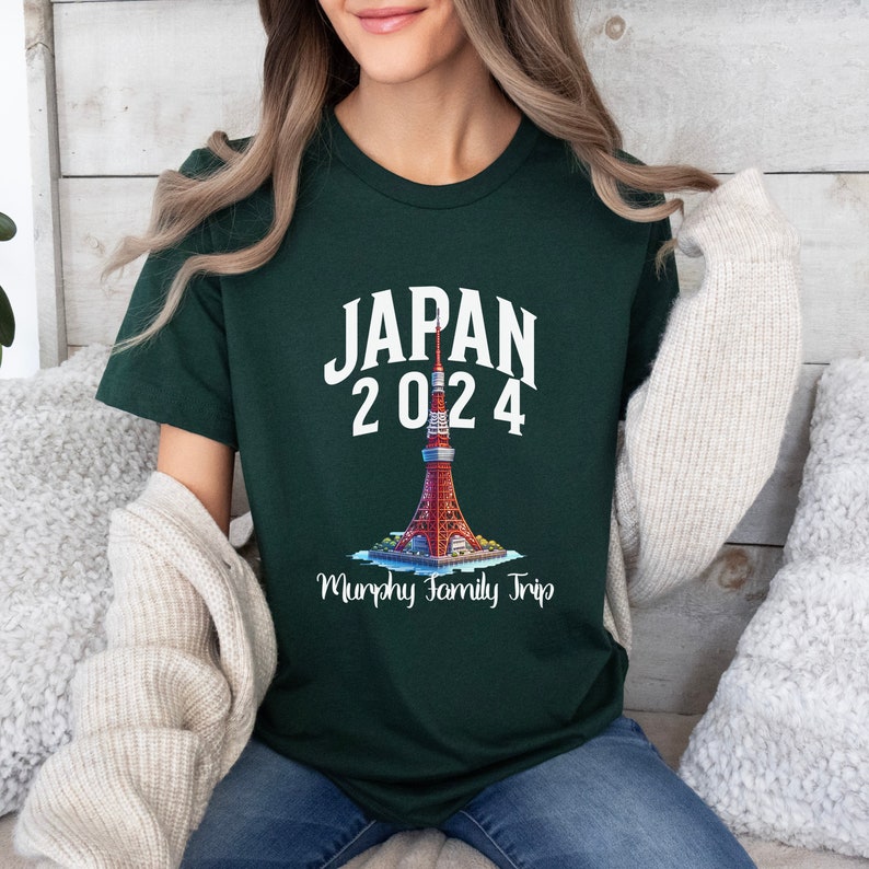 K&ouml;nnte beinhalten: Ein dunkelgr&uuml;nes T-Shirt mit wei&szlig;em Text, der "JAPAN 2024" lautet, und einer Grafik des Tokyo Skytree. Unter der Grafik steht der Text "Murphy Family Trip".