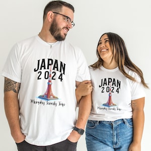 K&ouml;nnte beinhalten: Ein Paar tr&auml;gt wei&szlig;e T-Shirts mit einer Grafik des Tokyo Skytree und dem Text "JAPAN 2024 Murphy Family Trip".