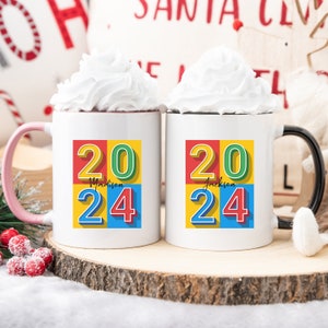 May include: Two white ceramic mugs with black handles. The mugs have a colorful design with the numbers 20 and 24 in a block style font. The mugs are personalized with the names "Madison" and "Jackson".