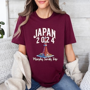 K&ouml;nnte beinhalten: Ein maroonfarbenes T-Shirt mit wei&szlig;em Text, der "JAPAN 2024" lautet, und einer Grafik des Tokyo Towers. Unter dem Turm steht der Text "Murphy Family Trip".
