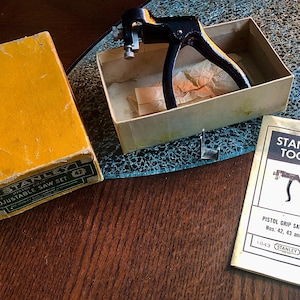 Peut inclure: Ensemble de scie réglable Stanley Tools vintage, comprenant une scie à poignée pistolet noire, dans sa boîte d'origine. L'ensemble comprend une boîte jaune avec du texte vert et un livret avec le texte "Stanley Tools".