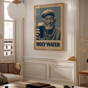May include: Framed art print featuring a smiling elderly man holding a pint of dark beer. The artwork has a vintage style with the words "HOLY WATER" in bold letters at the bottom. The man is wearing a cap and a sweater.