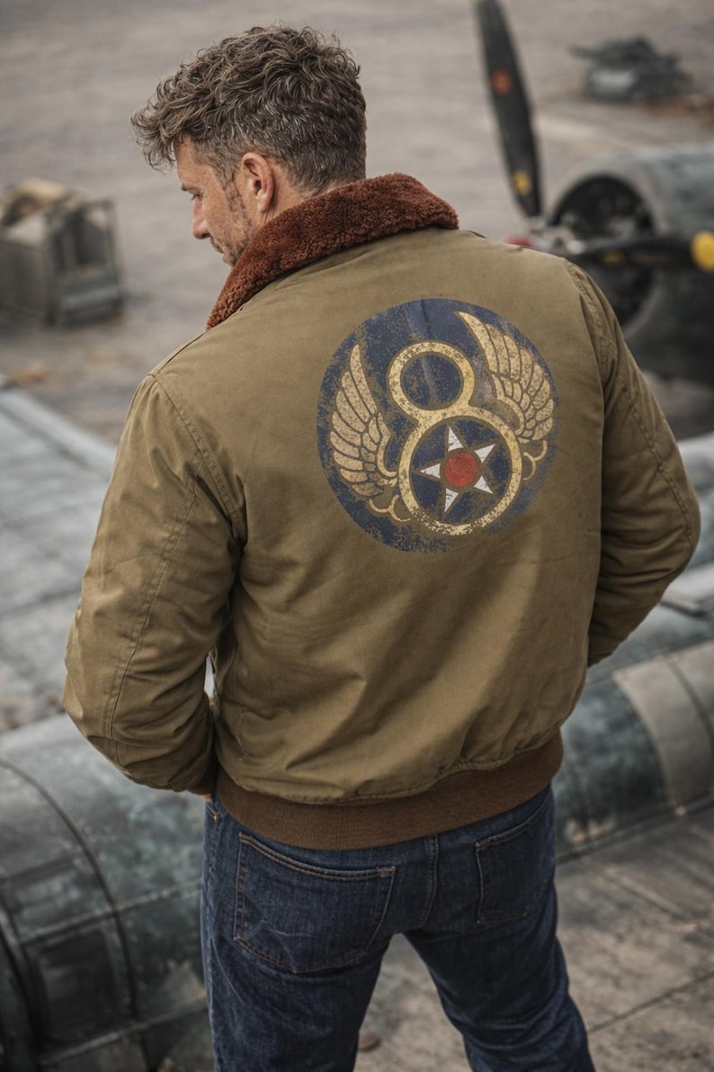 May include: Olive green bomber jacket with a brown faux fur collar and a circular patch on the back. The patch features a blue circle with a white star and the number 8, flanked by wings. The jacket has a ribbed hem and cuffs.