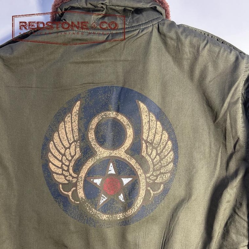 May include: An olive green jacket with a circular emblem featuring wings, a number eight, and a star. The jacket has a fur-lined hood. The text "REDSTONE & CO" is visible. Vintage style.