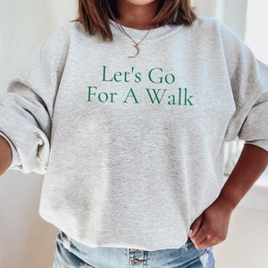 May include: A gray sweatshirt with the text "Let's Go For A Walk" in green lettering.
