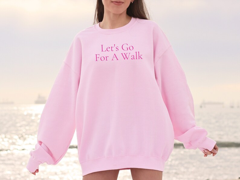 May include: A pink sweatshirt with the text "Let's Go For A Walk" in pink lettering.
