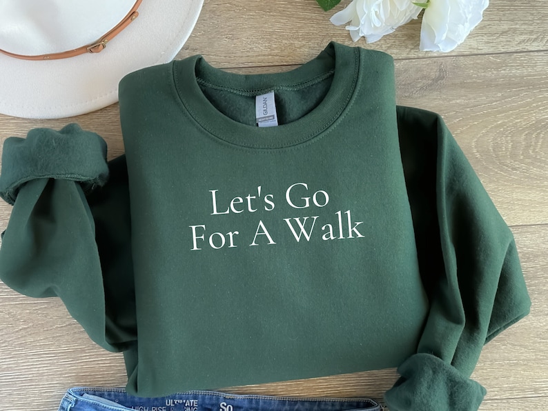 May include: A dark green sweatshirt with the text "Let's Go For A Walk" in white lettering.