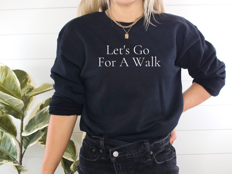 May include: A black sweatshirt with the text "Let's Go For A Walk" in white lettering.