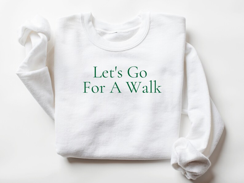 May include: White sweatshirt with green text that reads "Let's Go For A Walk".