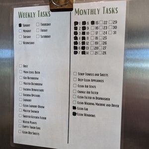 Puede incluir: Una lista de tareas semanales y mensuales en un refrigerador de acero inoxidable. La lista se titula "Tareas semanales" y "Tareas mensuales". Las tareas semanales incluyen "Polvo", "Ba&ntilde;o del nivel principal", "Ba&ntilde;o de los ni&ntilde;os", "Ba&ntilde;o principal", "Aspirar las escaleras de abajo", "Aspirar las escaleras de arriba", "Lavander&iacute;a", "Limpiar la sala de lavander&iacute;a", "Ducha principal", "Fregar el piso de la cocina", "Regar las plantas", "Vaciar los botes de basura", y "Cambiar las s&aacute;banas". Las tareas mensuales incluyen "Cambiar las toallas y las s&aacute;banas", "Limpiar a fondo los electrodom&eacute;sticos", "Limpiar las rejillas de ventilaci&oacute;n", "Cambiar el filtro de aire", "Limpiar el filtro del lavavajillas", "Limpiar la lavadora y la secadora", "Lavar el coche", y "Limpiar las ventanas".