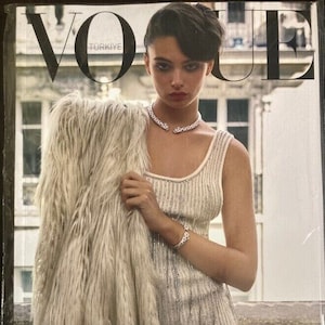 May include: A magazine cover featuring a woman wearing a white sequined dress and a fur coat. The magazine is titled "Vogue Türkiye" and the text "Retro İhtişam" is printed below the woman.