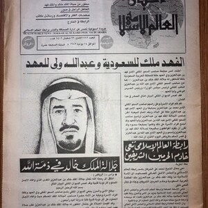 May include: A black and white newspaper clipping with a photo of a man in a white robe and a black and white patterned head covering. The headline reads "The King of Saudi Arabia and the Crown Prince".
