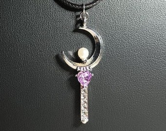 May include: A silver crescent moon pendant necklace with a purple heart and white pearl accents. The necklace is on a black cord.