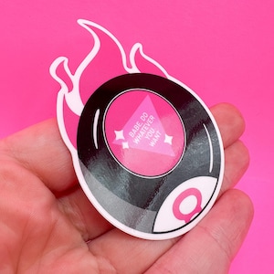 May include: A pink sticker featuring a stylized magic 8-ball design with a flame-like border. The 8-ball has a pink center with the text "Babe do whatever you want". The sticker is on a pink background.