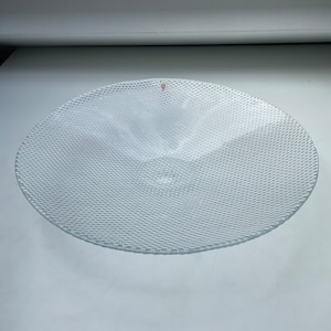 May include: A clear glass serving bowl with a textured, raised pattern. The bowl is round and has a slight curve to the sides.