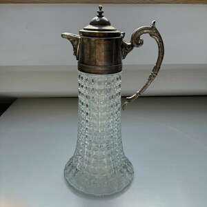 May include: A silver and clear glass jug with a textured glass body and a silver lid and handle.