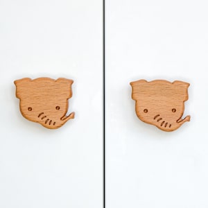 Peut inclure: Deux poignées de tiroir en bois en forme d'éléphant avec une finition brun clair. Le motif d'éléphant est sculpté dans le bois et a un aspect mignon et cartoon.