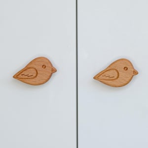 Peut inclure: Deux boutons de porte en bois en forme d'oiseau. Les boutons sont de couleur brun clair et présentent un design simple et sculpté.