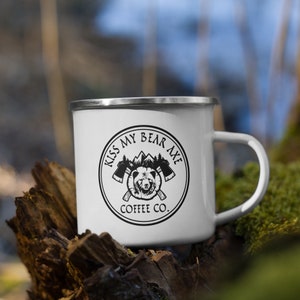 May include: White enamel camping mug with a black and white logo that says "Kiss My Bear Axe Coffee Co." and features a bear with crossed axes.