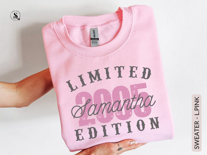 K&ouml;nnte beinhalten: Ein hellrosa Sweatshirt mit dem Text "LIMITED 2005 Samantha EDITION" in Grau und Rosa. Das Sweatshirt hat einen Rundhalsausschnitt und ist gefaltet. Das Bild zeigt ein Kleidungsst&uuml;ck.