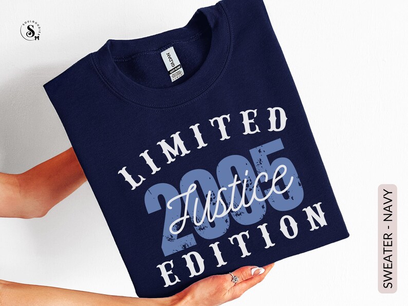 K&ouml;nnte beinhalten: Marineblaues Sweatshirt mit dem Text "LIMITED 2005 Justice EDITION" in Wei&szlig; und Blau. Das Sweatshirt wird von einer Person gehalten. Die Worte "SWEATER - NAVY" sind vertikal auf der rechten Seite aufgedruckt.