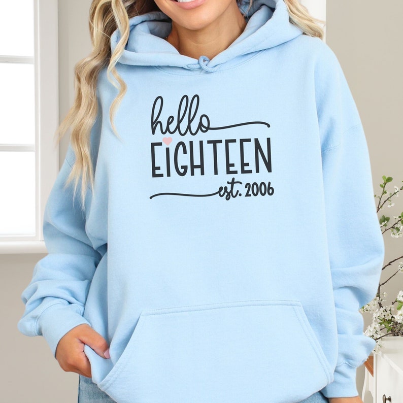 cute girl wearing oversize hoodie with hello 18 est 2006 light blue print in front birthday gift for 18th Birthday trendy College Style