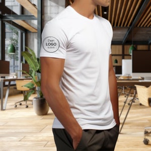man stading at work place with white shirt logo print in black on left sleeve