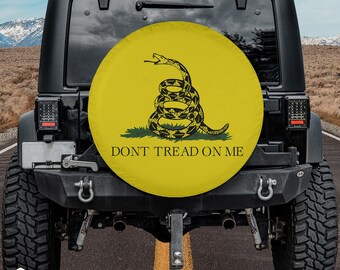 May include: A black Jeep Wrangler with a yellow spare tyre cover featuring a coiled rattlesnake and the text "Don't Tread On Me".