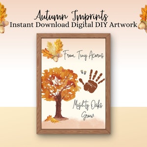 May include: A printable autumn-themed craft for children. The image shows a brown wooden frame with a white background. The background has a watercolour painting of a tree with brown leaves and a handprint. The text "From Tiny Acorns Mighty Oaks Grow" is written in black cursive font.