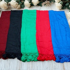 Op de afbeelding: Vijf kleurrijke sjaals in de kleuren bordeaux, zwart, groen, rood en blauw worden getoond. Elke sjaal heeft een gefranjerde rand. Witte rozen en groen zijn rond de sjaals gerangschikt op een licht houten oppervlak.