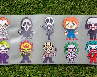 May include: A rectangular clear transfer sheet featuring ten colorful cartoon-style illustrations of horror movie characters, including Pennywise, Ghostface, Jack Skellington, Chucky, Billy the Puppet, Joker, Ghost Rider, Jason Voorhees, Beetlejuice, and Harley Quinn.