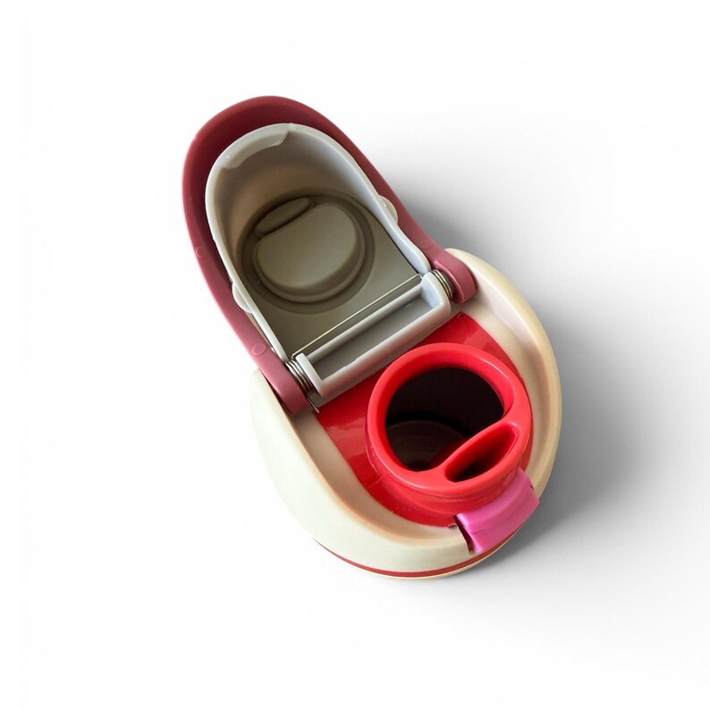 May include: A multi-colored kitchen gadget with a white, red, and pink design. The gadget has a circular opening and a pivoting mechanism. The design includes a peeler and a handle. The item is designed for food preparation.