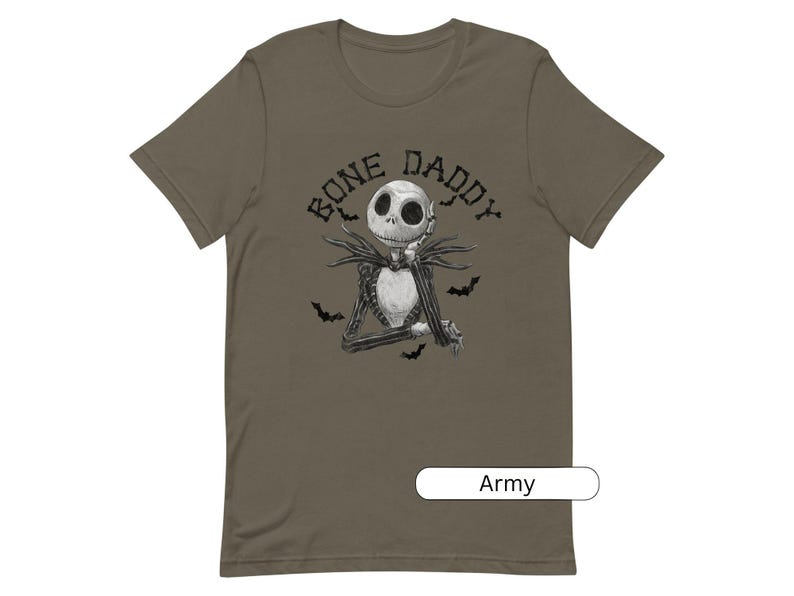 Puede incluir: Una camiseta verde con una ilustraci&oacute;n en blanco y negro de un personaje esqueleto con el texto "Bone Daddy" encima. La camiseta est&aacute; disponible en verde militar.