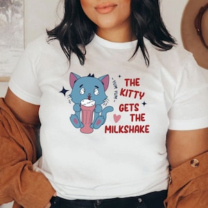 May include: White t-shirt with a blue cartoon cat holding a milkshake and the text "The Kitty Gets The Milkshake".