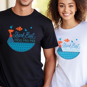 以下が含まれることがあります： 白い背景に、青い魚とオレンジ色の火山、そして「Shark Bait Hoo Ha Ha」という文字が書かれたグラフィックデザインが施されたTシャツ2枚です。