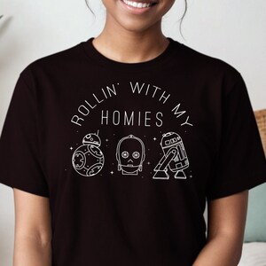 May include: Black t-shirt with a white graphic design that says "Rollin' with my homies" and features three Star Wars characters: R2-D2, C-3PO, and BB-8.
