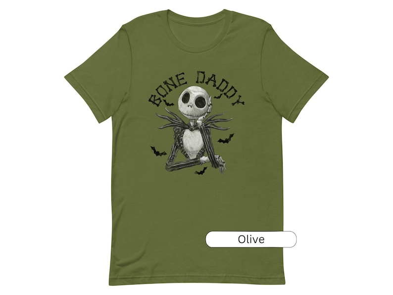 Puede incluir: Camiseta verde oliva con una ilustraci&oacute;n en blanco y negro de Jack Skellington de Pesadilla antes de Navidad. El texto "Bone Daddy" est&aacute; impreso en negro sobre la ilustraci&oacute;n.