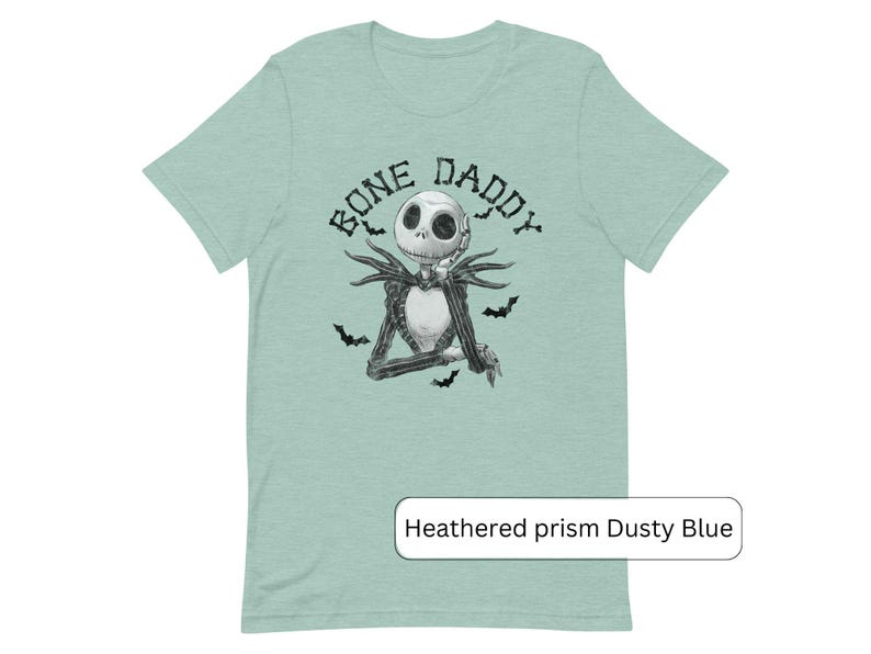 Puede incluir: Una camiseta azul claro con una ilustraci&oacute;n en blanco y negro de Jack Skellington de Pesadilla antes de Navidad. El texto "Bone Daddy" est&aacute; impreso sobre la ilustraci&oacute;n.