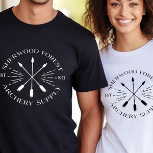 May include: Two people wearing black and white t-shirts with a white logo that says "Sherwood Forest Archery Supply Est. 1973" with a graphic of arrows in a circle.