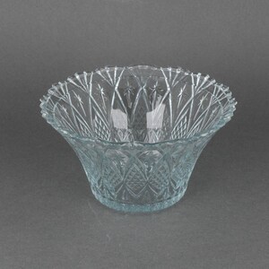 Puede incluir: Un cuenco de vidrio transparente con un borde festoneado y intrincados patrones en forma de diamante. El cuenco está hecho de vidrio grueso y tiene una estética vintage delicada.