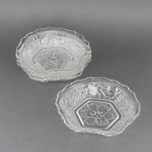 May include: Set of four clear glass bowls with a scalloped edge and a floral design. The bowls are stacked on top of each other.