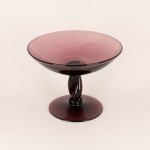 May include: A purple glass bowl with a twisted stem and a wide, shallow bowl.