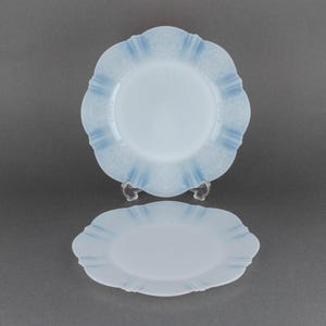 Puede incluir: Dos platos de vidrio azul claro con borde festoneado y un delicado diseño en relieve. Los platos están apilados uno encima del otro.