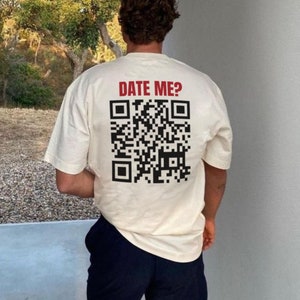 May include: A white t-shirt with a black and white QR code and the text "DATE ME?" printed on the back.