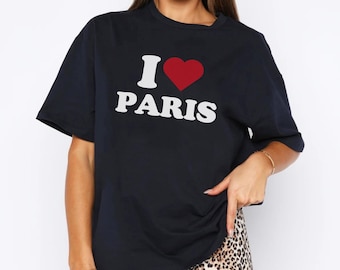 May include: Navy blue t-shirt with the text "I ♥ PARIS" in white and a red heart. The shirt is paired with leopard print shorts. The t-shirt has short sleeves and a crew neck.